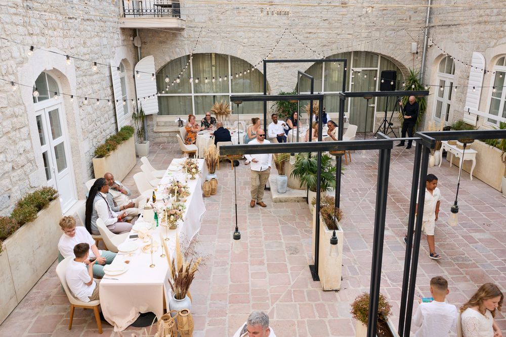 Elegant outdoor courtyard reception with long white dining tables and string lights in a stone-walled venue.