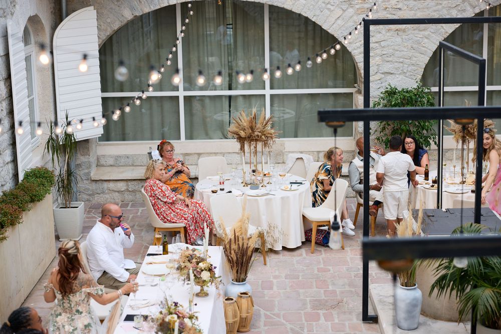 Guests celebrate at an elegant outdoor wedding reception with string lights and white decor.