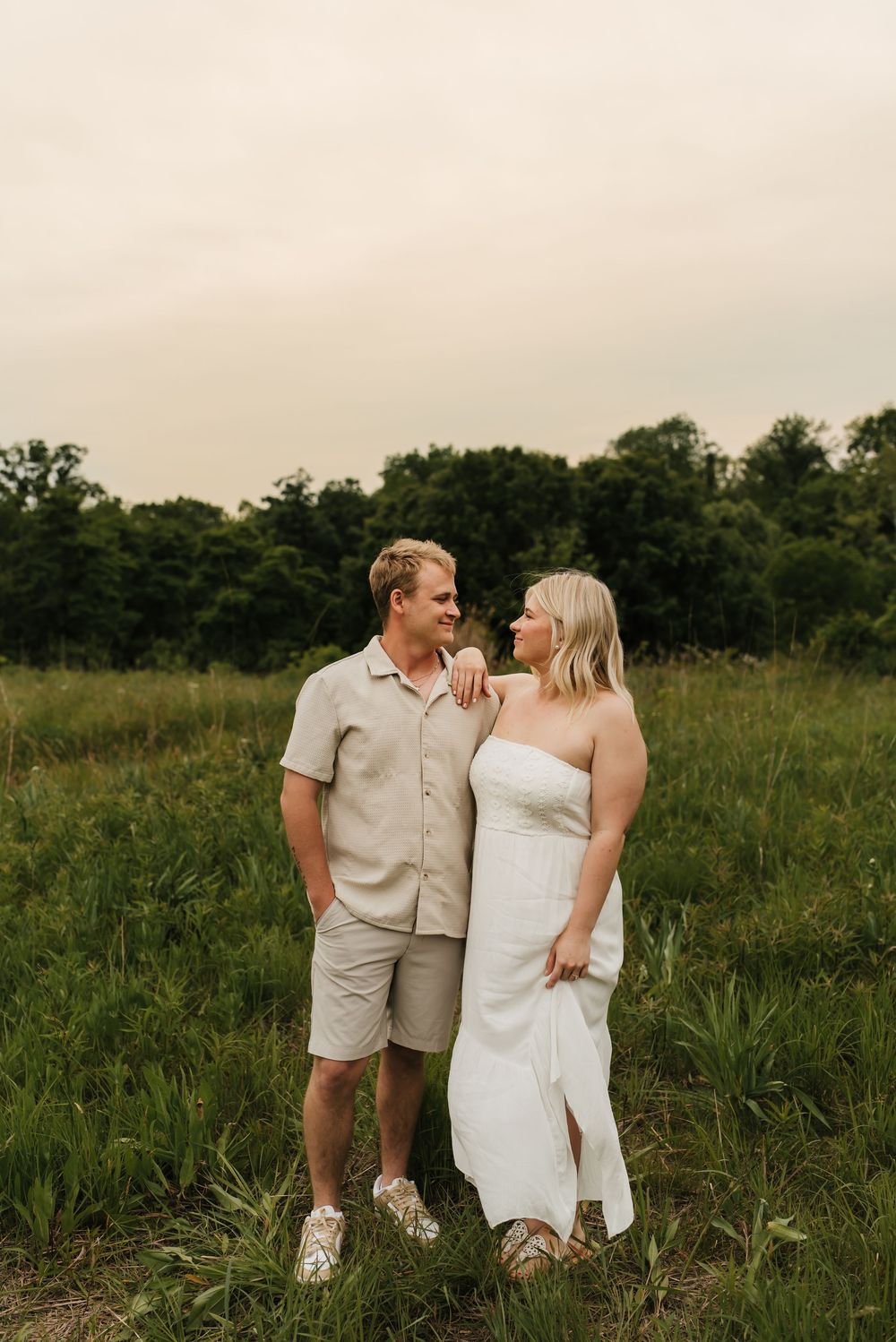 Couple laughing together during a candid engagement session outdoors.