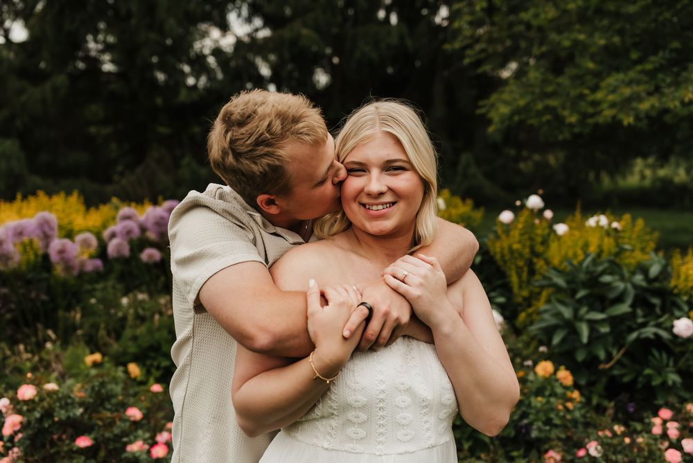 Engaged couple embracing in a sunlit field during an outdoor engagement session.