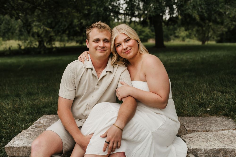 Engaged couple embracing in a sunlit field during an outdoor engagement session.
