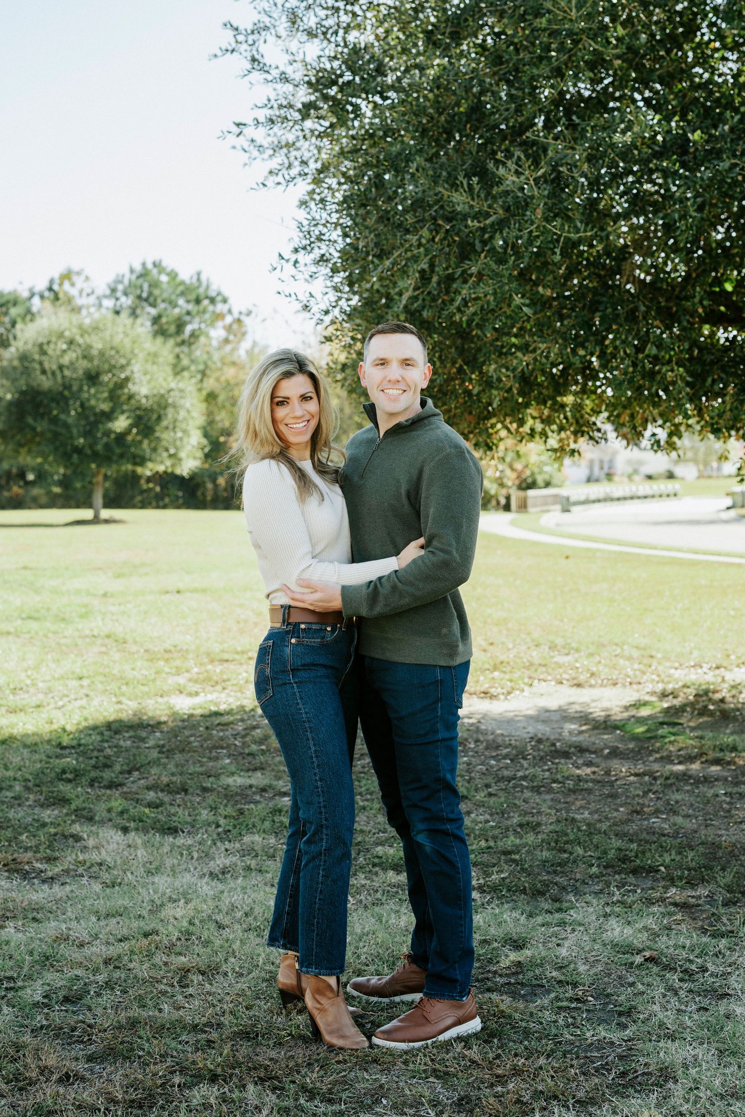 A couple shares an intimate moment together on a sunny day in a park setting.