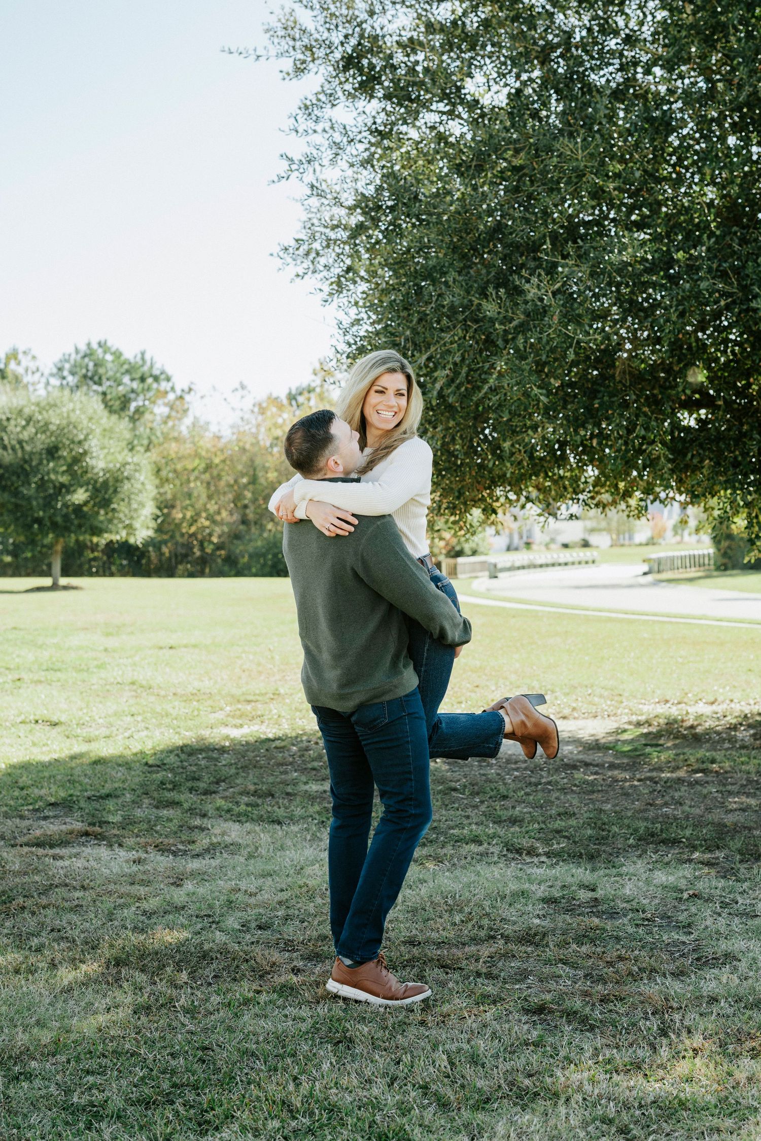 A couple shares a romantic moment in a grassy field on a sunny autumn day.