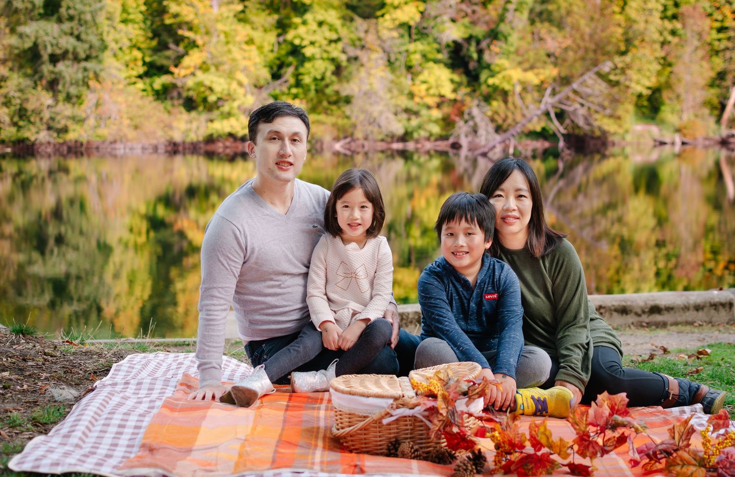 Family sitting together by the lake during a fall photoshoot at Lake Fenwick Park in Kent.