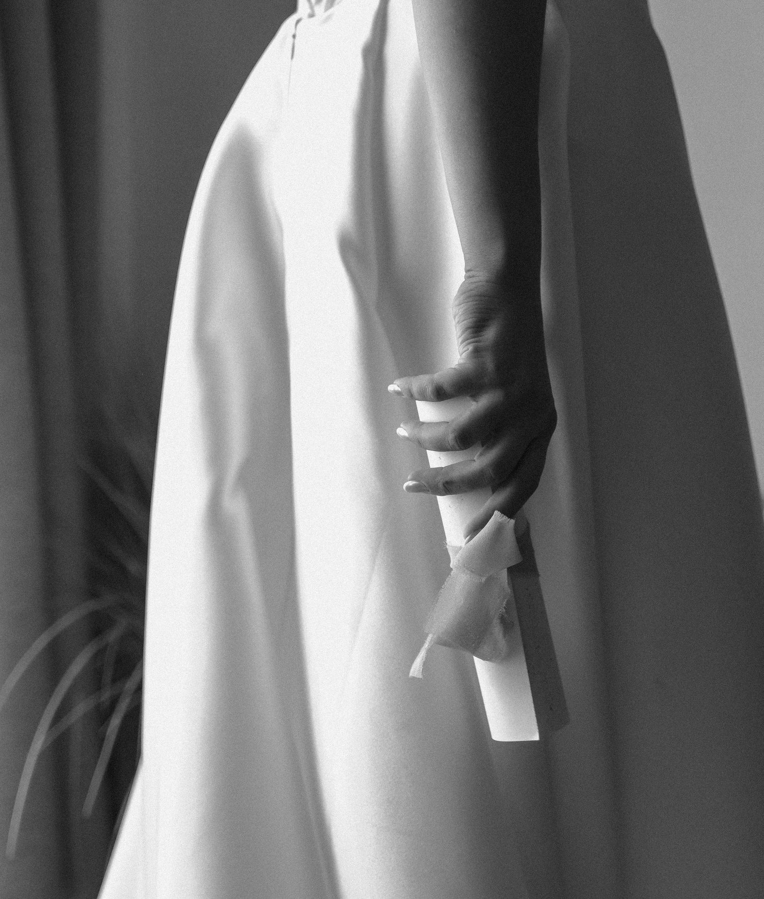 Dramatic black and white detail of flowing white wedding dress fabric against dark background.