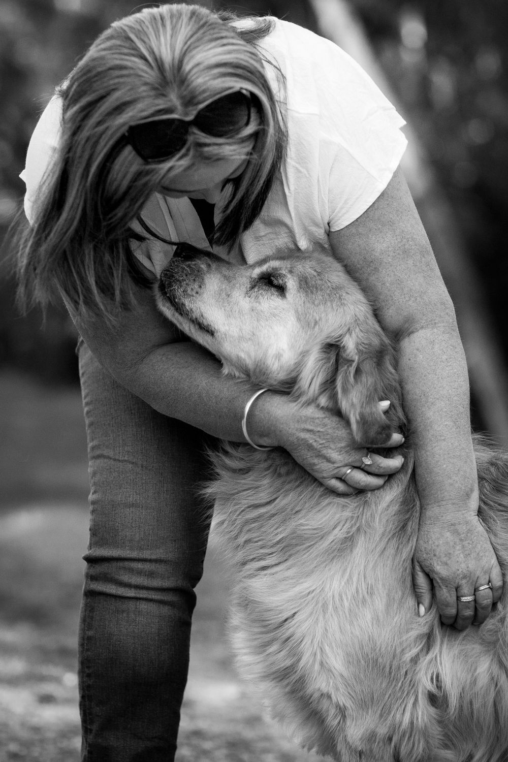 A tender black and white moment between owner and Golden Retriever dog showing affection and connection outdoors.