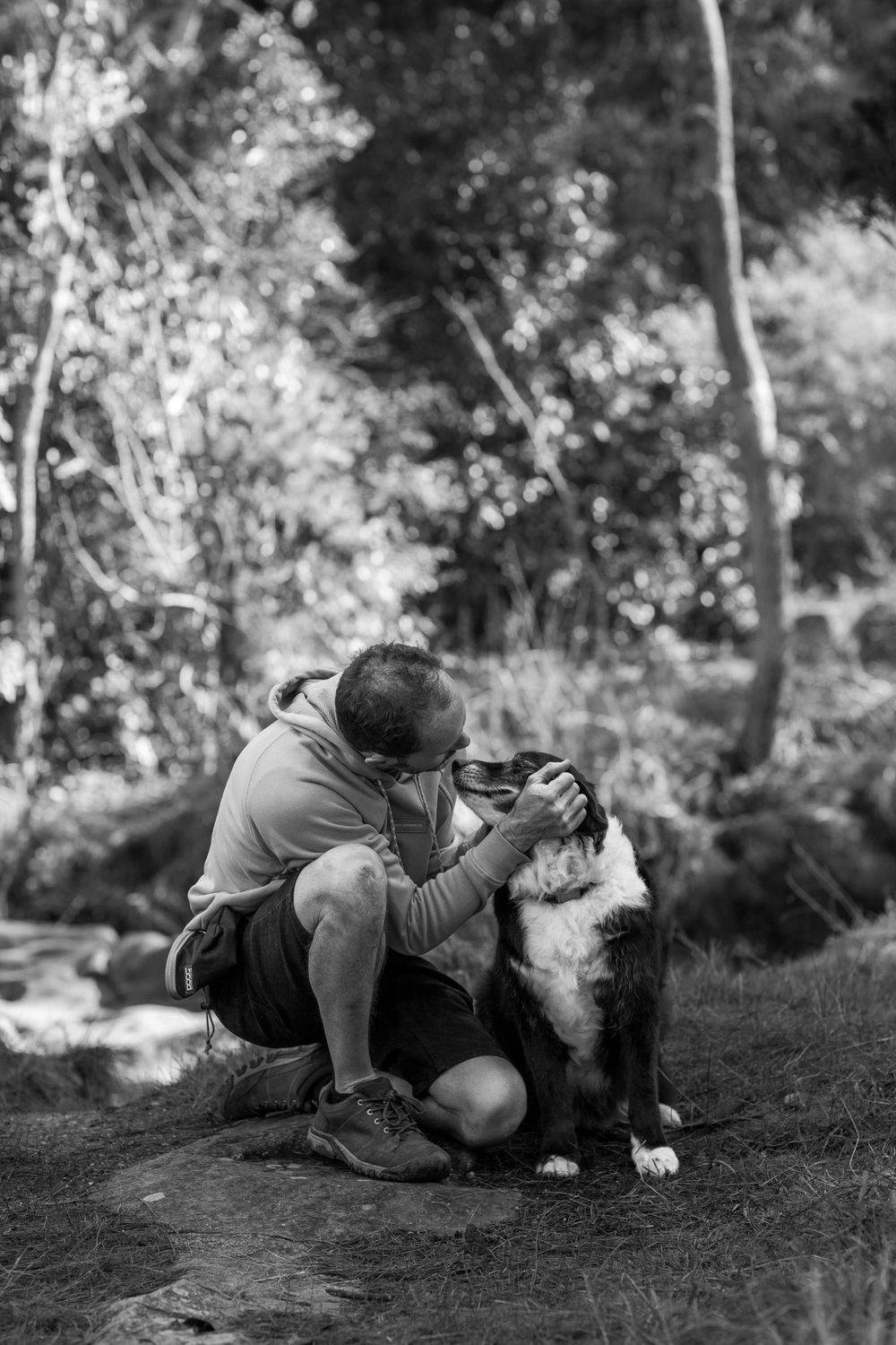 Dog and companion sharing a tender moment in black and white photography.