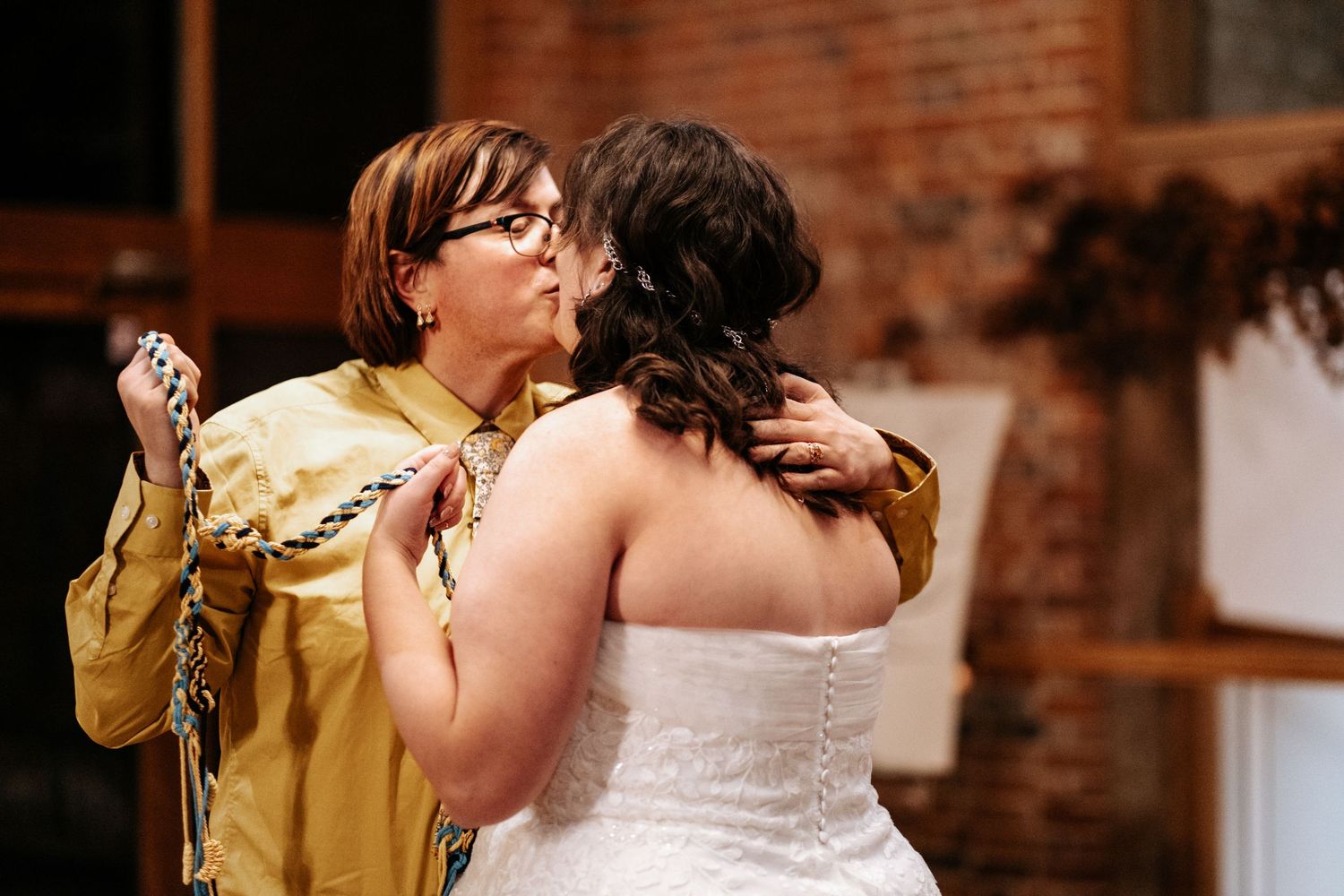 An intimate wedding celebration moment in a rustic brick-walled venue.