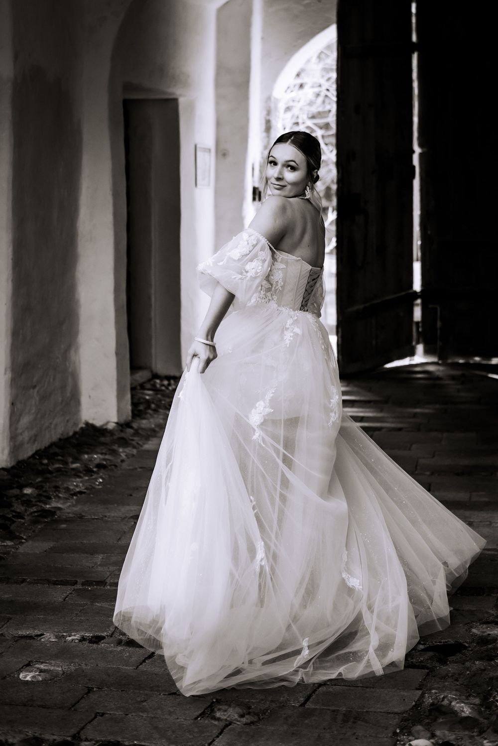 Artistic black and white photos of a bride in flowing dress moving gracefully through a dark corridor.