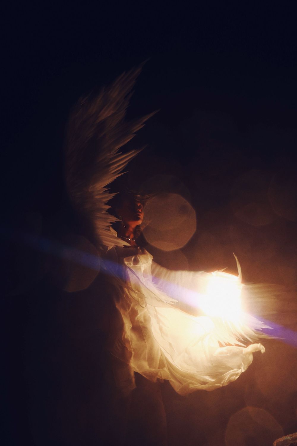 A glowing white ethereal shape floats against a dark background creating a mystical light trail effect.