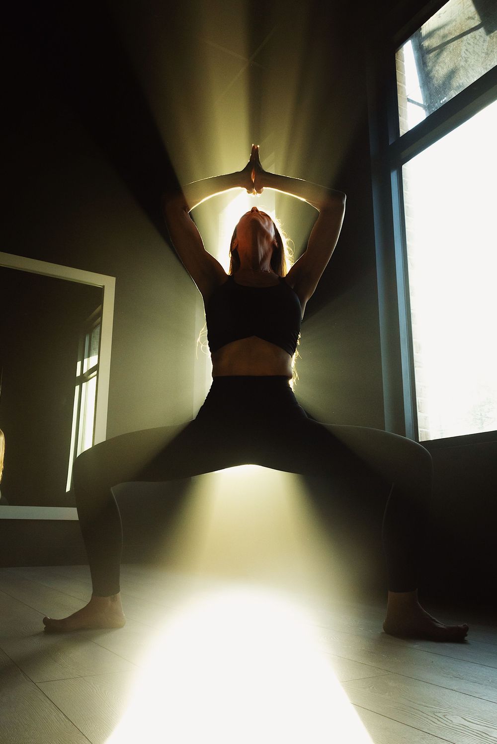 A silhouetted figure creates dramatic shadows on a light floor in a sequence of artistic dance-like movements.