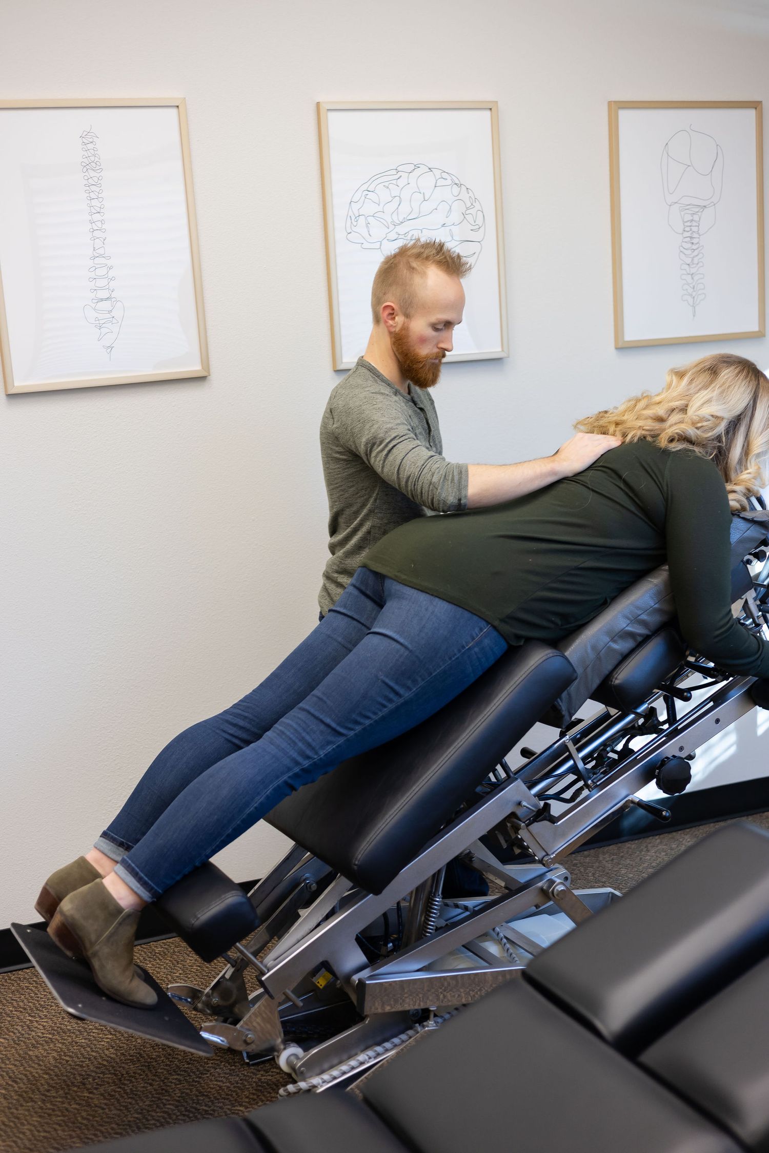 chiropractor branding photo in Sumner, WA wellness health man support pregnant woman on adjustment table to support and care