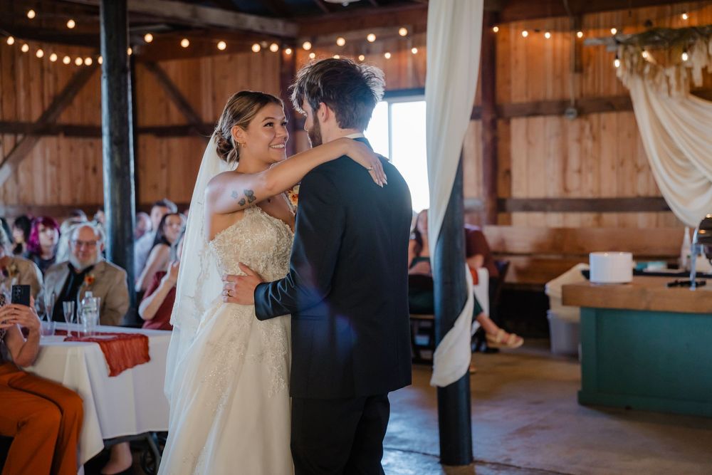 Elegant wedding celebration inside a rustic barn venue with string lights and romantic ambiance.