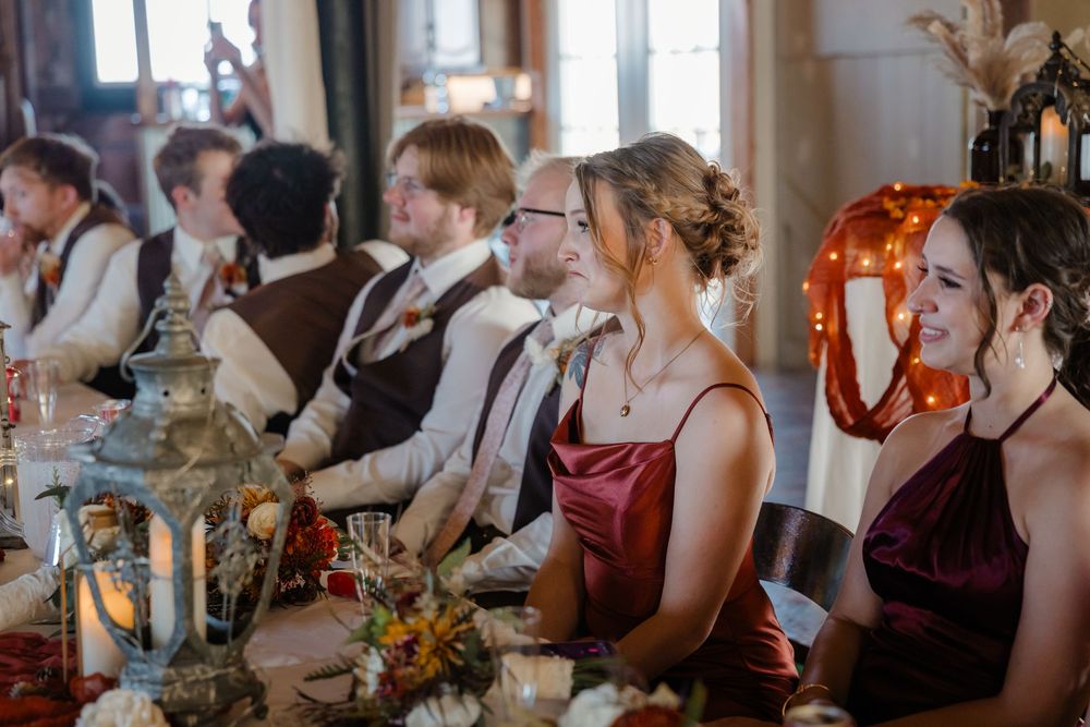 Wedding guests seated at an elegantly decorated table with lanterns and autumn floral arrangements.