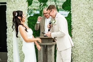 A couple sharing a moment during their wedding ceremony in front of a floral wall backdrop.