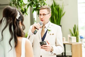 Wedding party posing in an indoor garden setting with natural greenery and white decor.