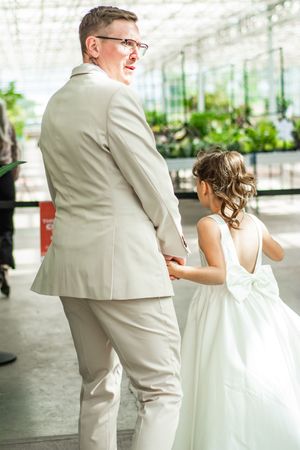 Couple in white and beige attire dancing in a bright indoor space.