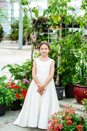 A wedding photo shoot in a greenhouse with white dresses and colorful flowers in the background.