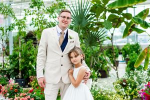 Wedding party members walking through a lush greenhouse setting.