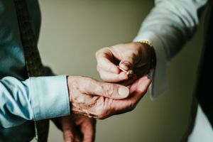 Close-up shot of hands exchanging or adjusting a ring during a wedding ceremony.
