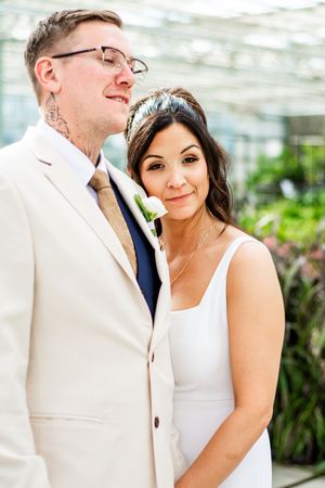 An intimate wedding portrait captured in a greenhouse with natural lighting.
