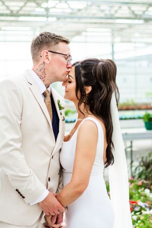 A romantic wedding moment captured in a greenhouse setting.