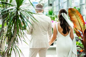 Elegant wedding photos captured in a greenhouse surrounded by tropical plants.