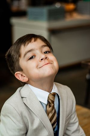 Young boy in a light gray suit and striped tie makes playful expressions in a series of portraits.