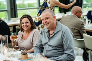Wedding guests enjoying drinks and conversation at a reception table.