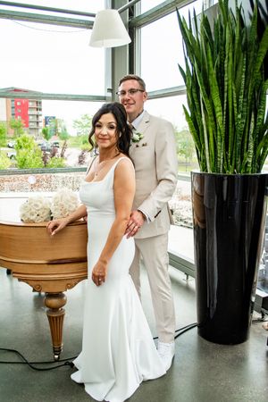 Wedding couple poses in an elegant indoor space with modern decor and potted plants.