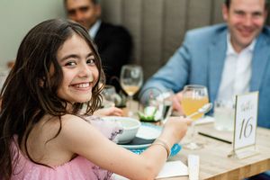 Guests enjoying a formal dining event with wine glasses and table settings at a numbered table.