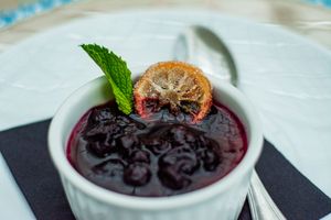 Elegant plated desserts with dark berry sauce and mint garnish on white dishes.