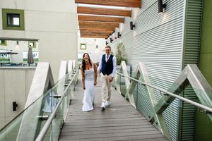 Modern architectural hallway with green accents and wooden beams leads to outdoor area.