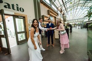 Wedding guests mingle in a bright indoor atrium with glass ceiling and retail shops.