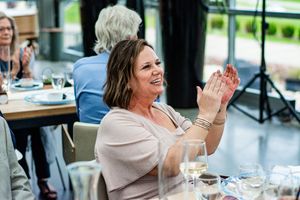 Wedding guests enjoying a celebration dinner and raising glasses in toast at an indoor reception venue.