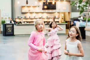 Young dancers in pink tutus practice ballet moves together at a dance studio.
