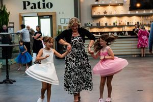Couples dancing together at an indoor venue with glass ceiling and patio signage.