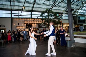 Wedding couple performs their first dance in a modern venue with glass ceiling and white decor.