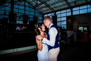 Wedding guests dancing and celebrating on a dimly lit dance floor at an evening reception.
