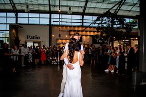 Wedding reception dance floor under glass atrium ceiling with string lights.