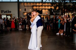 A romantic first dance at a wedding reception with guests watching in the background.