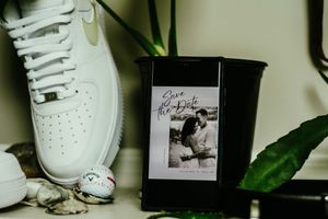 White sneakers and shoes displayed on shelves with decorative plants and photographs.