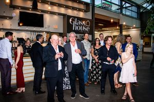 Wedding reception guests mingle and socialize in front of illuminated retail storefronts.