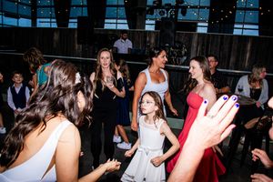 Wedding party dancing and celebrating with hands raised on a lively dance floor.