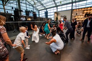 Wedding reception dance floor filled with guests celebrating under glass ceiling.