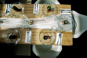 Rustic table settings with wooden chargers and clear glass plates for a wedding reception.