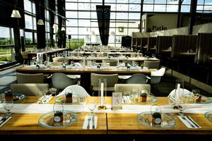Modern wedding reception venue with long wooden tables and industrial ceiling details.