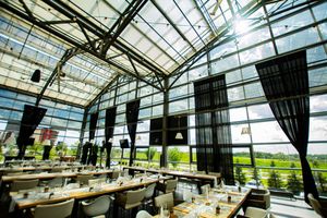 Modern glass-ceiling venue with elegant table settings and dramatic natural lighting.