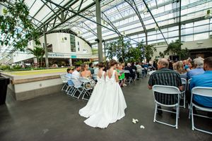 Wedding ceremony setup in a greenhouse-style venue with rows of chairs and natural lighting.