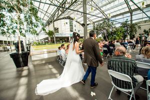Wedding celebration in a greenhouse with natural light streaming through glass ceiling.